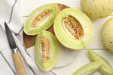 Photo of Fresh cut honeydew melons on white wooden table, flat lay