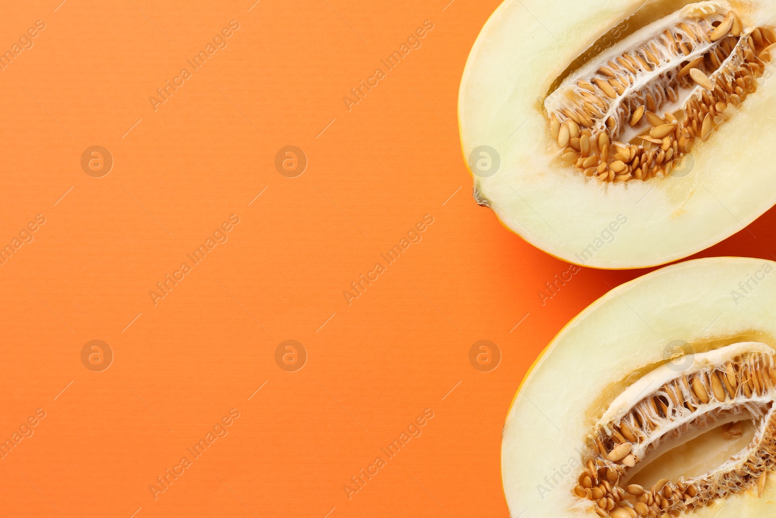 Photo of Halves of fresh melon on orange background, top view. Space for text