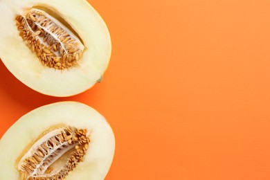 Photo of Halves of fresh melon on orange background, top view. Space for text