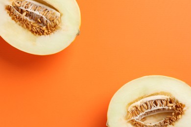 Halves of fresh melon on orange background, top view. Space for text