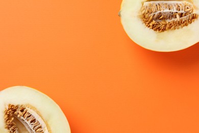 Photo of Halves of fresh melon on orange background, top view. Space for text