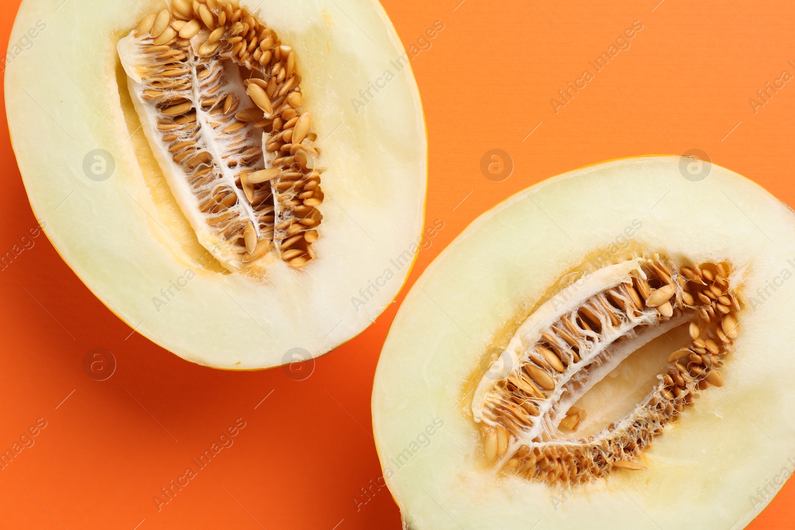 Photo of Halves of fresh melon on orange background, top view