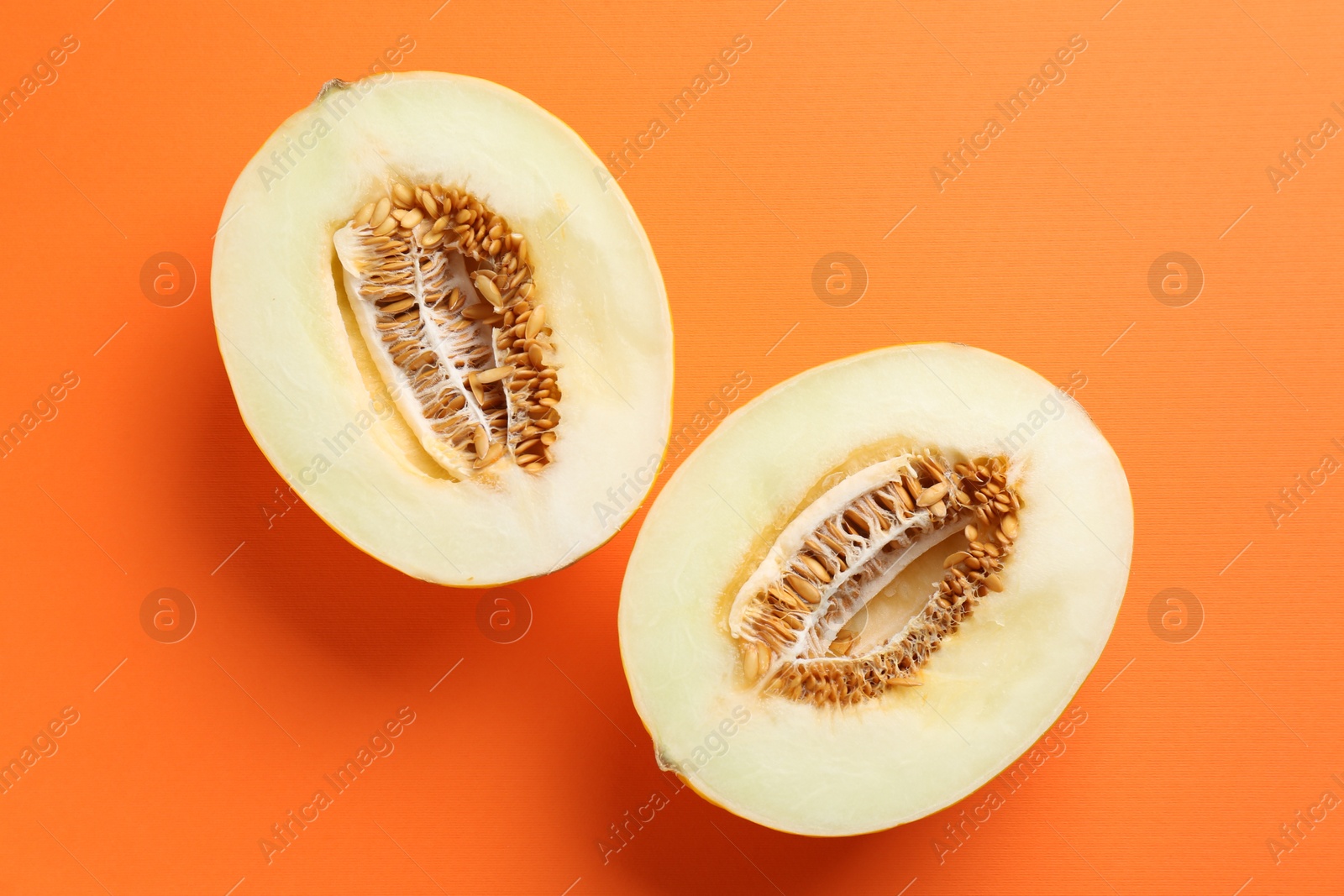 Photo of Halves of fresh melon on orange background, top view