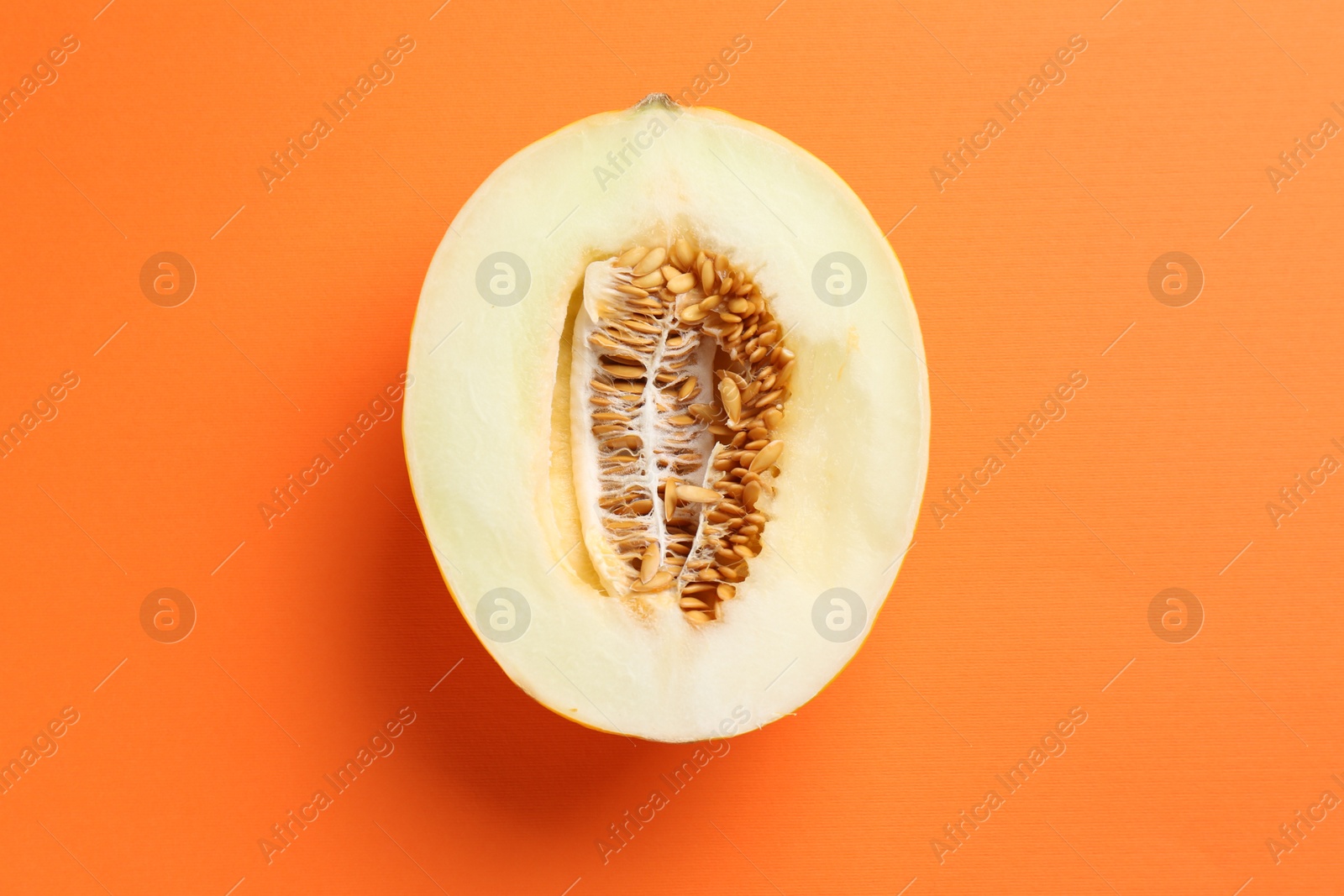 Photo of Half of fresh melon on orange background, top view