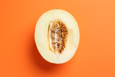 Half of fresh melon on orange background, top view