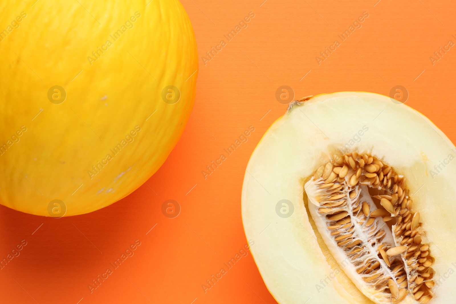 Photo of Whole and half of fresh melon on orange background, flat lay