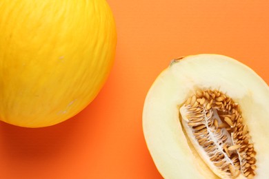 Whole and half of fresh melon on orange background, flat lay