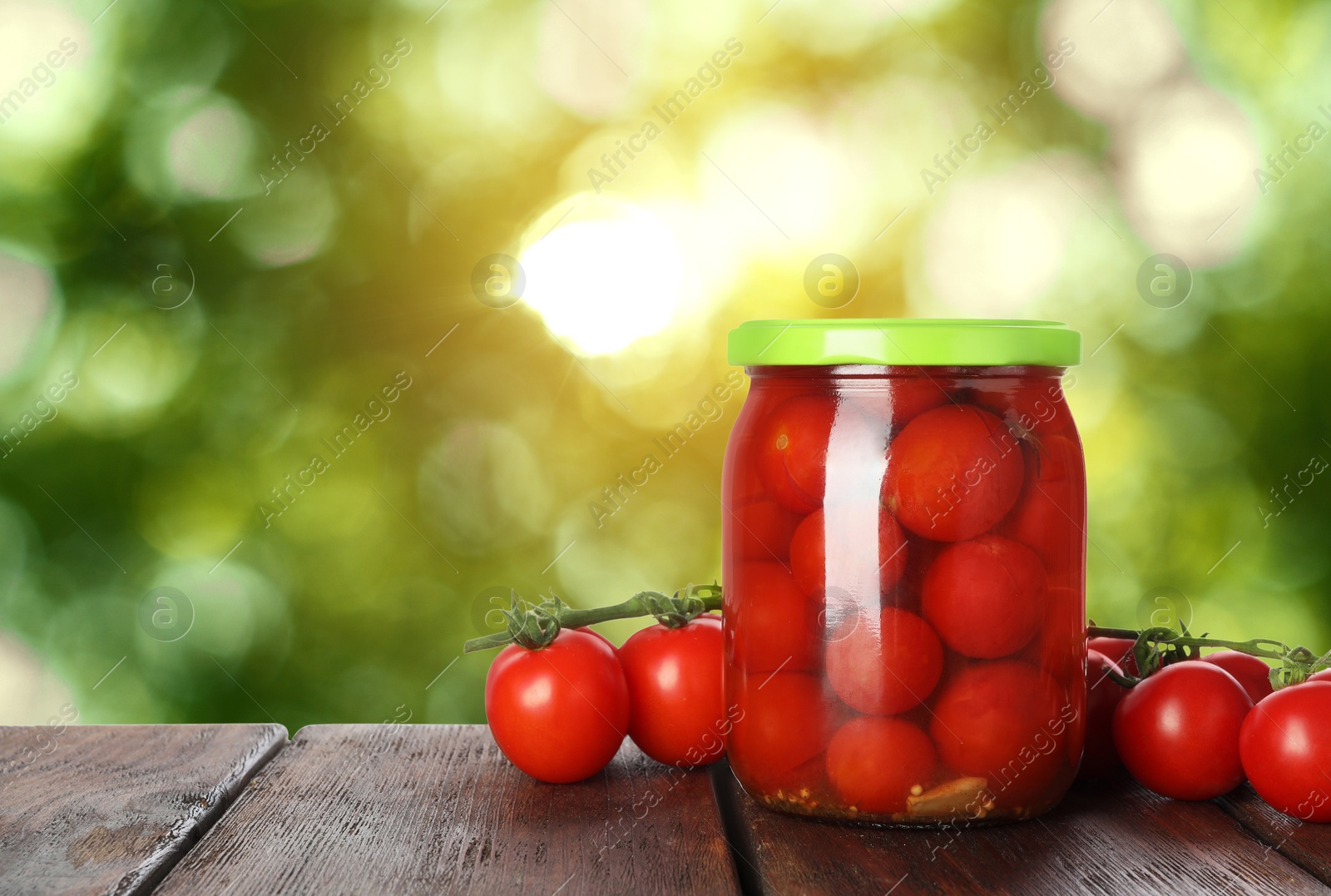 Image of Jar with pickled tomatoes on wooden table outdoors, space for text