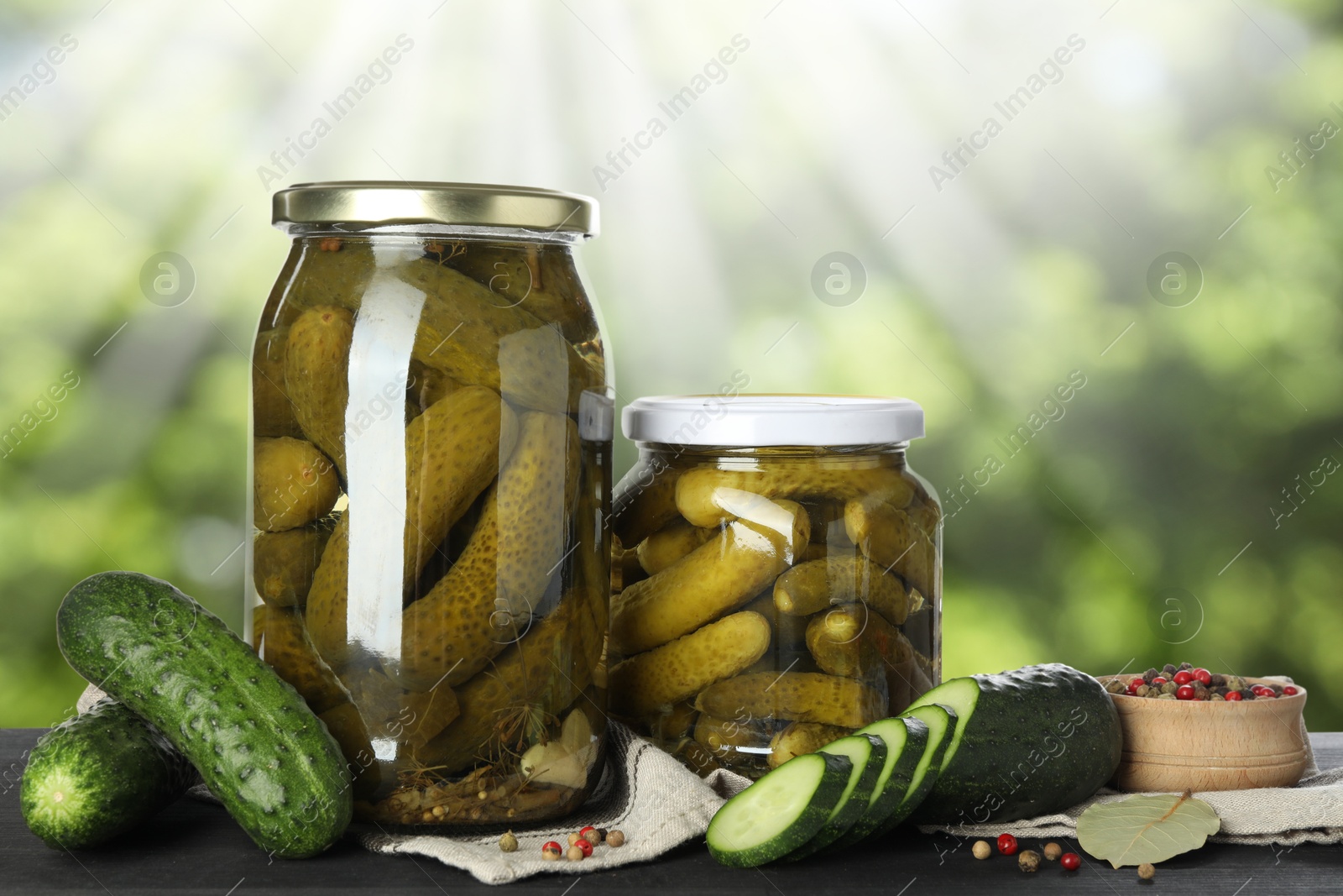 Image of Jars with pickled cucumbers on table outdoors, space for text