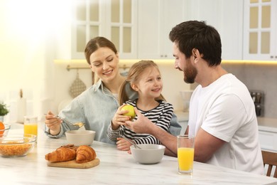 Happy family having breakfast at table in kitchen on sunny morning