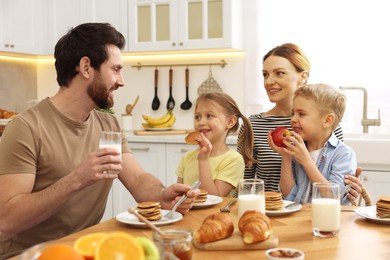 Image of Happy family having breakfast at table in kitchen on sunny morning