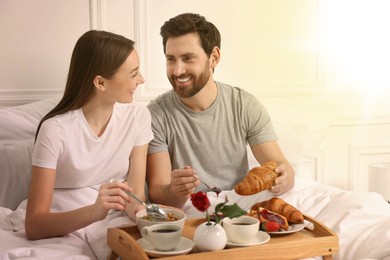 Image of Happy couple having breakfast in bedroom on sunny morning. Space for text