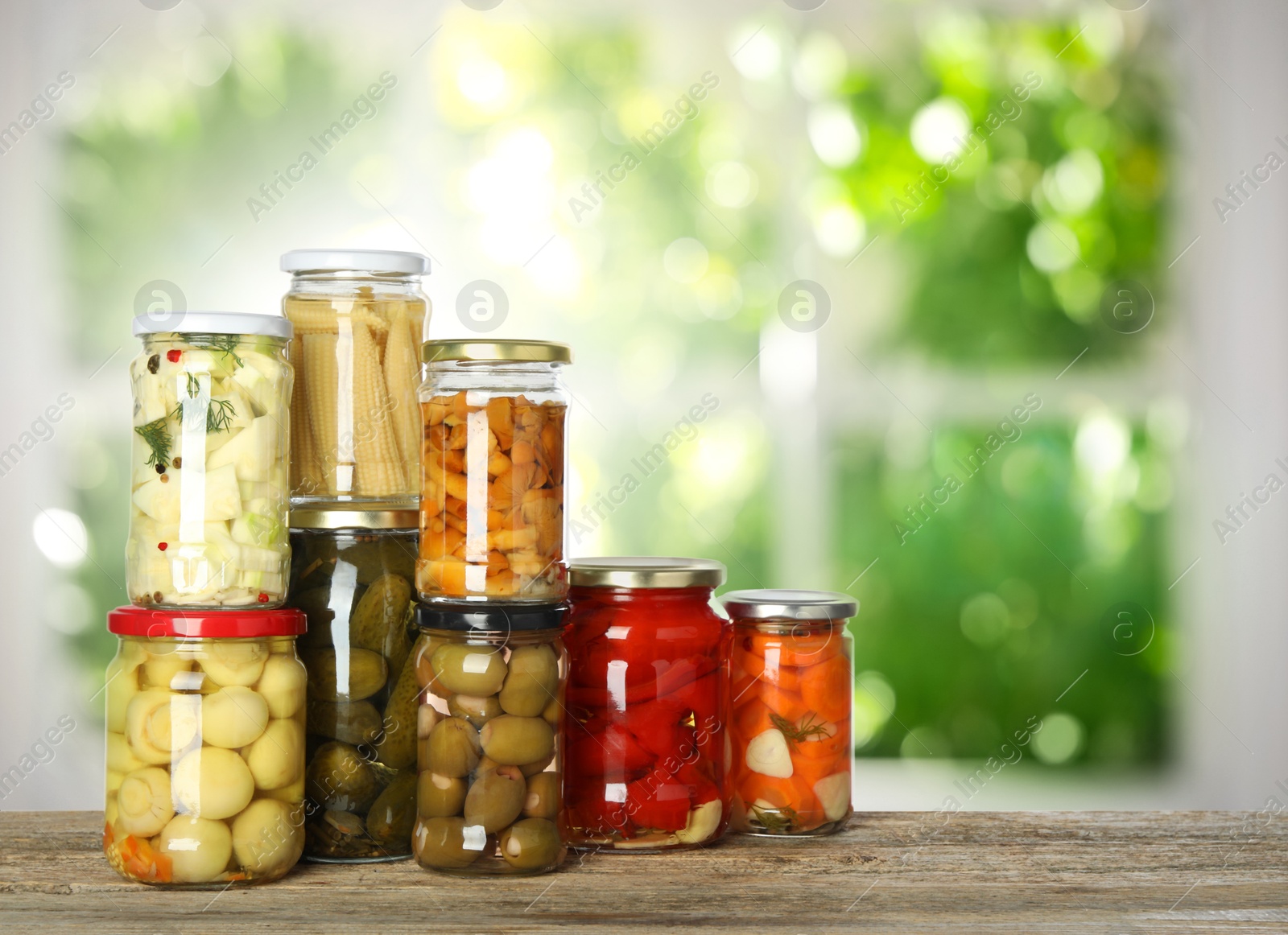 Image of Jars with pickled vegetables and mushrooms on wooden table indoors, space for text