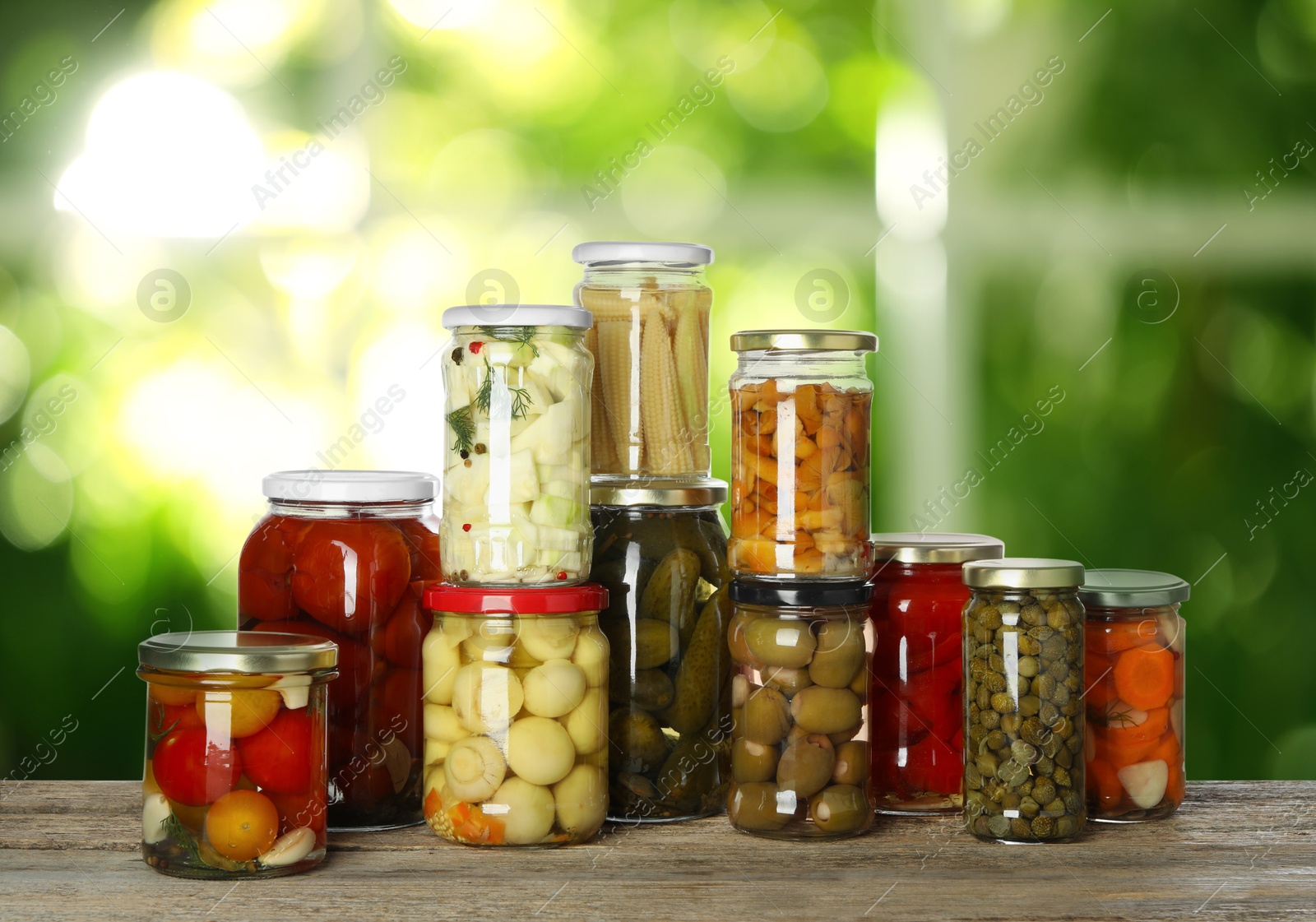 Image of Jars with pickled vegetables and mushrooms on wooden table indoors