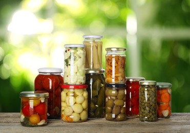 Image of Jars with pickled vegetables and mushrooms on wooden table indoors