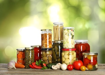 Image of Jars with pickled vegetables and mushrooms on wooden table indoors