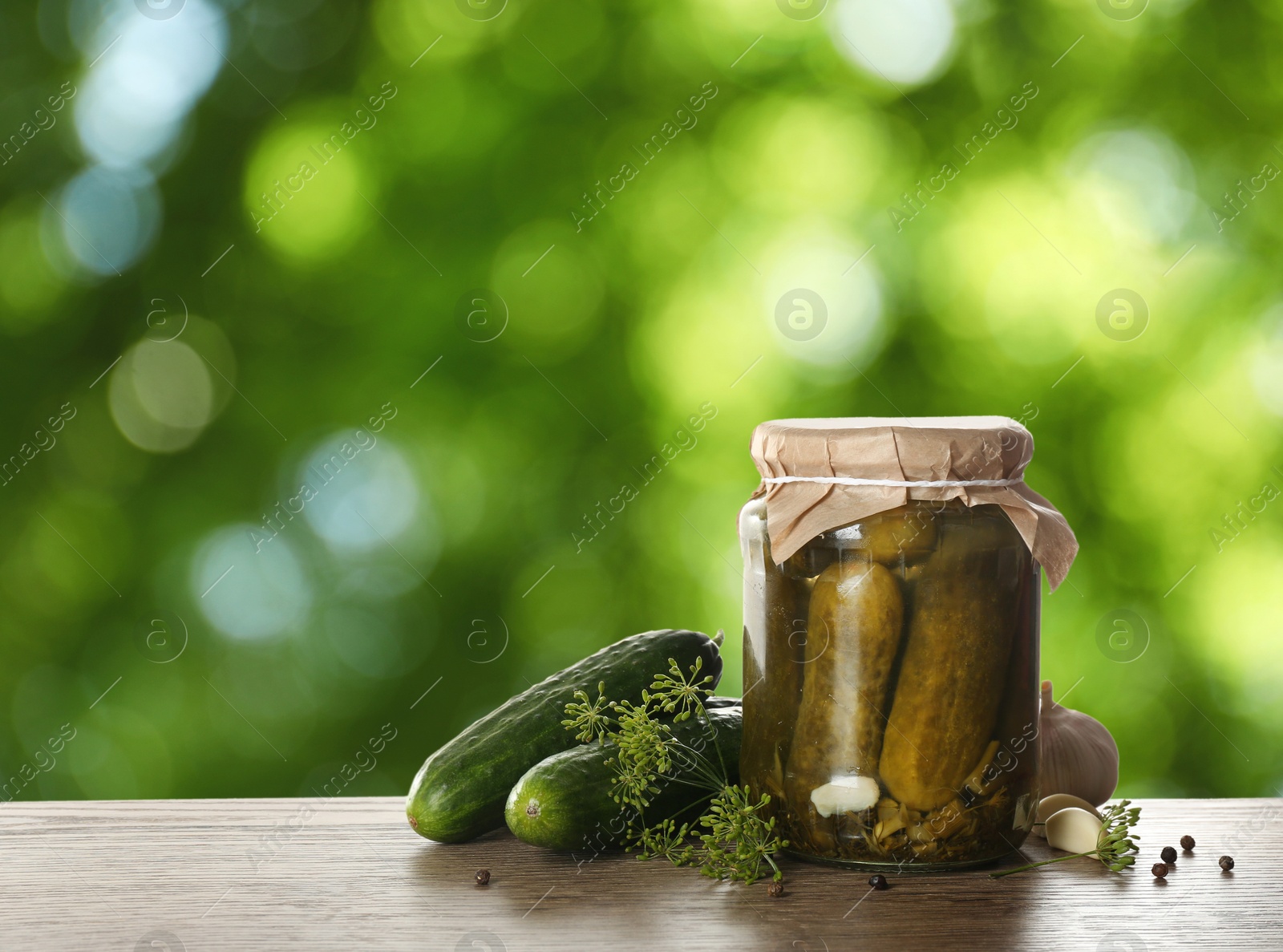 Image of Jar with pickled cucumbers on wooden table outdoors, space for text