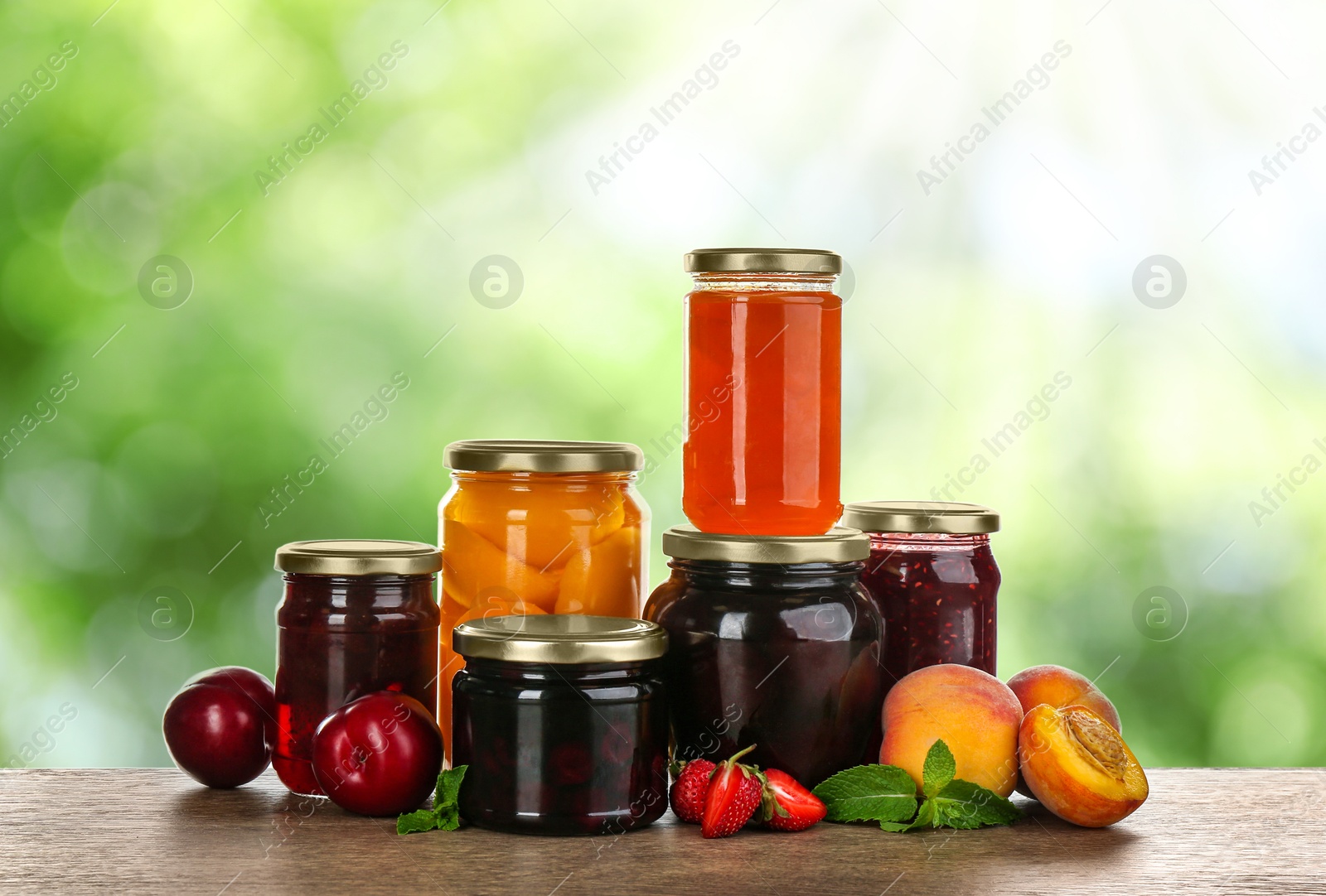 Image of Jars with jams and preserved fruits on wooden table outdoors