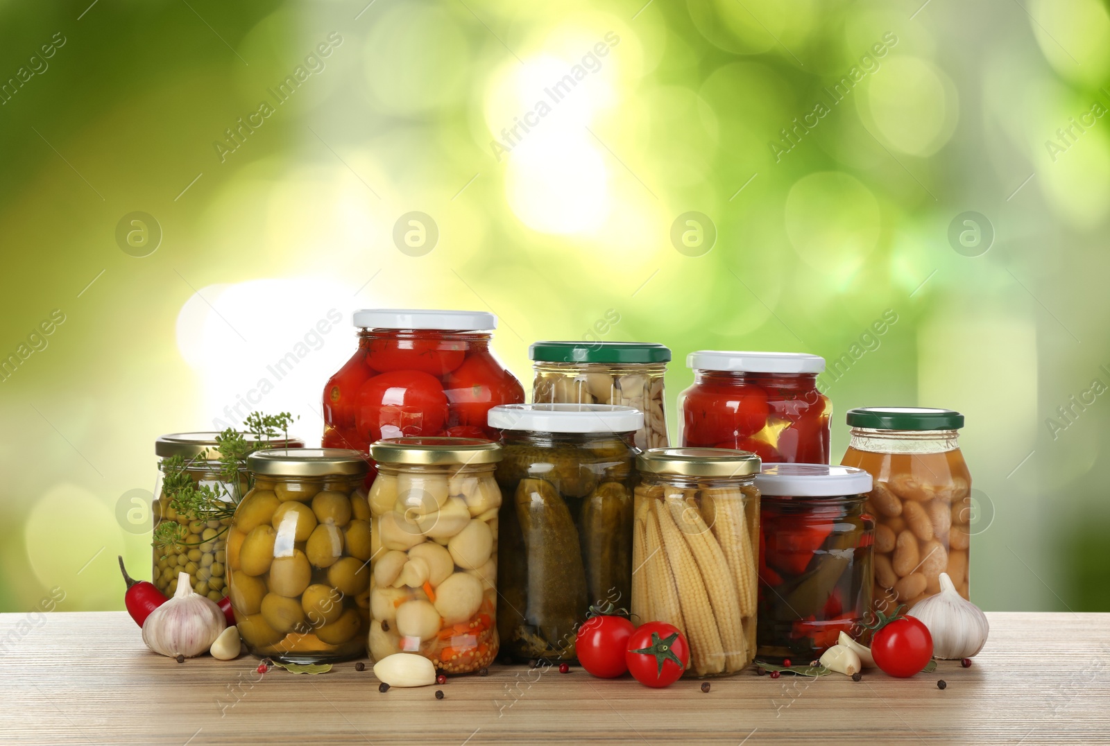 Image of Jars with pickled vegetables and mushrooms on wooden table outdoors, space for text