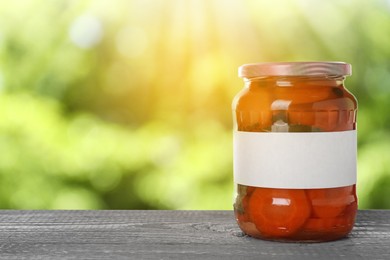 Image of Jar of pickled sliced carrots with blank label on wooden table outdoors, space for text