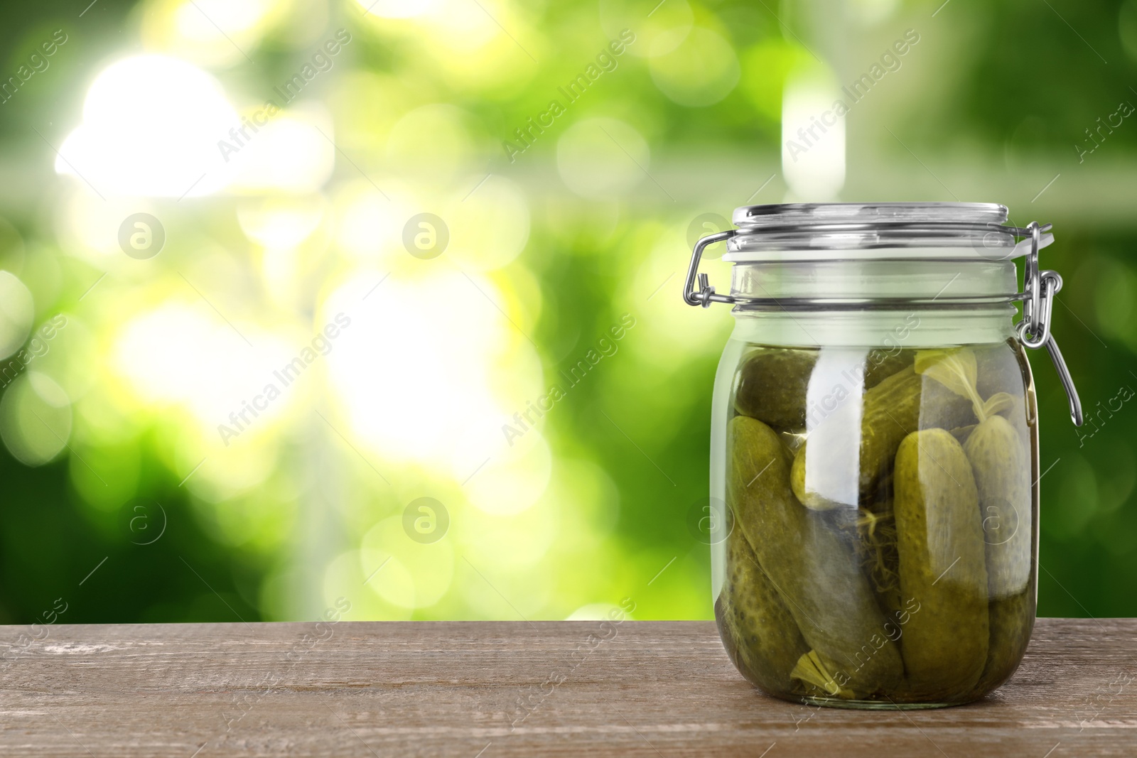 Image of Jar with pickled cucumbers on wooden table indoors, space for text