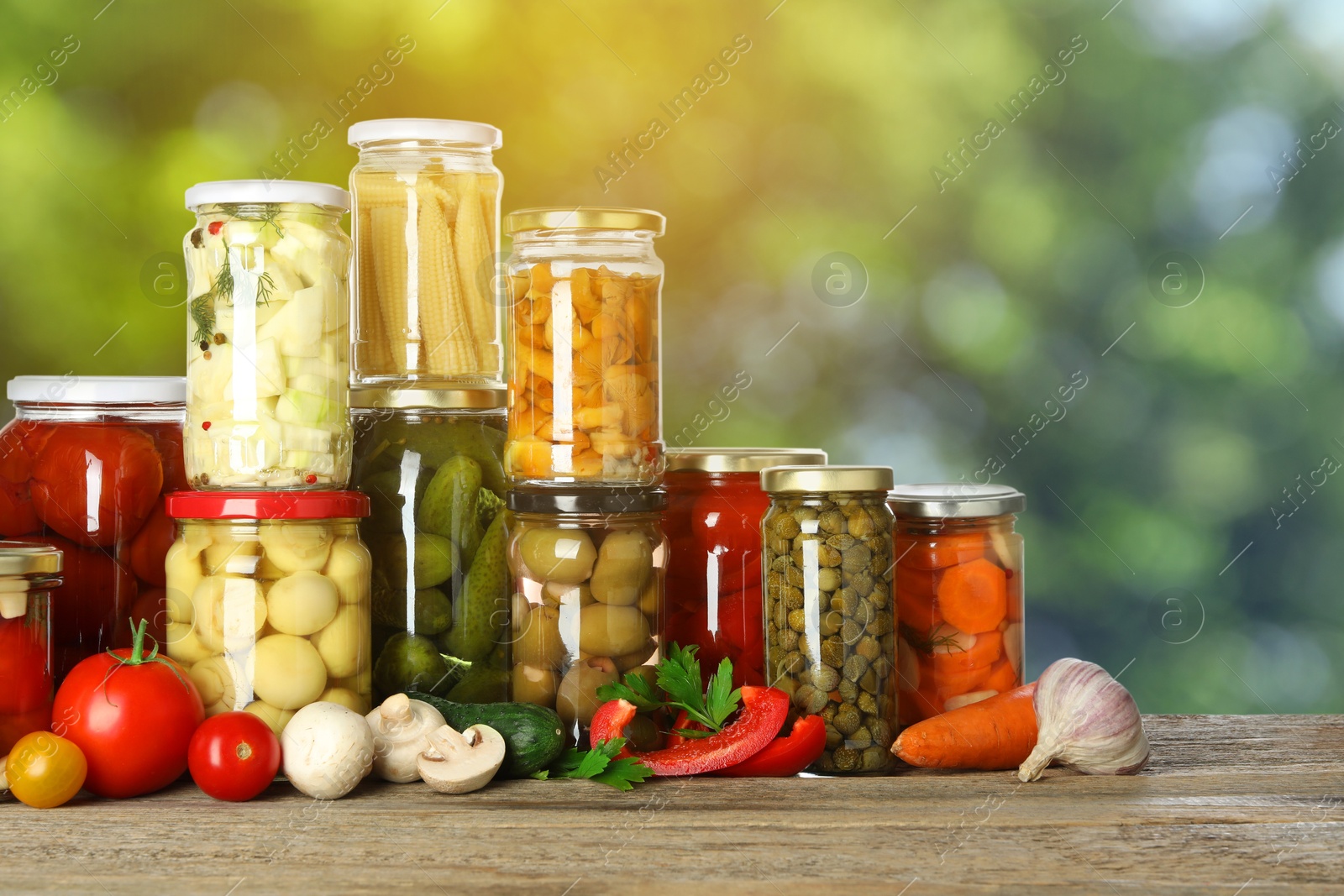 Image of Jars with pickled vegetables and mushrooms on wooden table outdoors, space for text