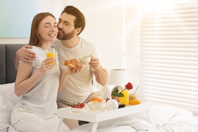 Lovely couple having breakfast in bedroom on sunny morning. Space for text