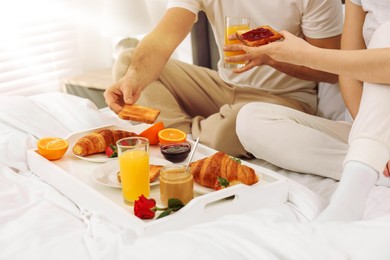 Couple having breakfast in bedroom on sunny morning, closeup