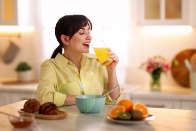 Smiling woman having breakfast in kitchen on sunny morning