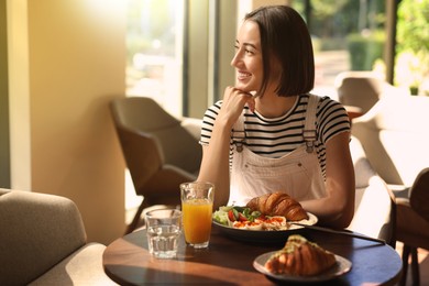 Image of Happy woman having tasty breakfast in cafe on sunny morning