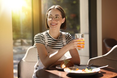 Image of Happy woman having tasty breakfast in cafe on sunny morning