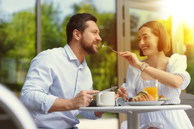 Image of Happy couple having breakfast at outdoor cafe on sunny morning