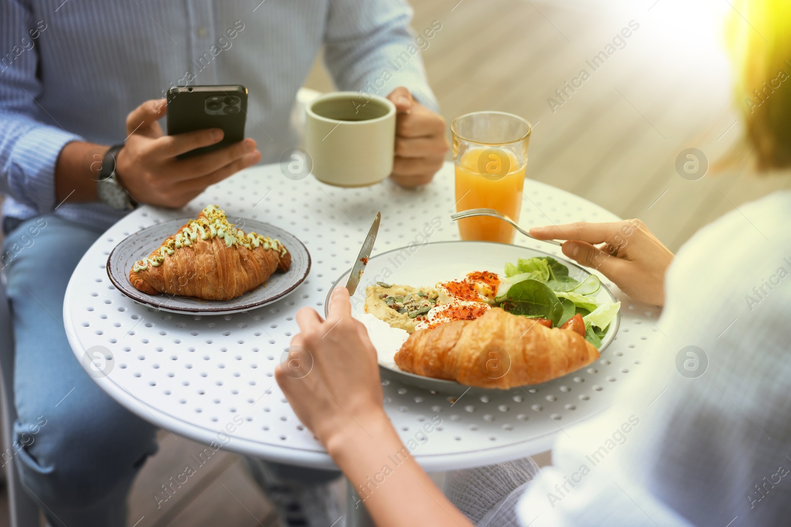 Image of Couple having breakfast at outdoor cafe on sunny morning, closeup