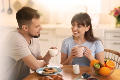 Happy couple having breakfast in kitchen on sunny morning