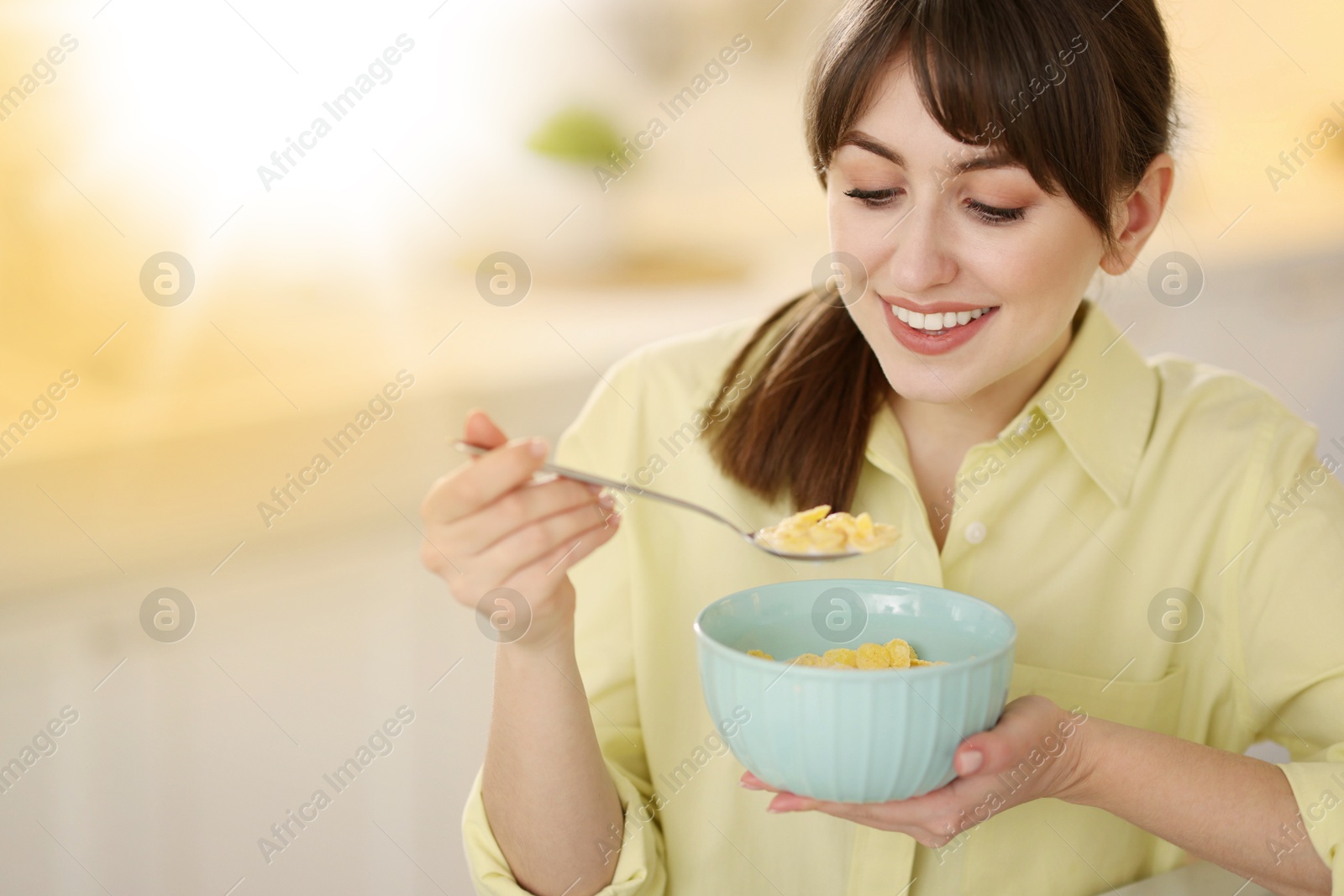 Image of Smiling woman having breakfast indoors on sunny morning