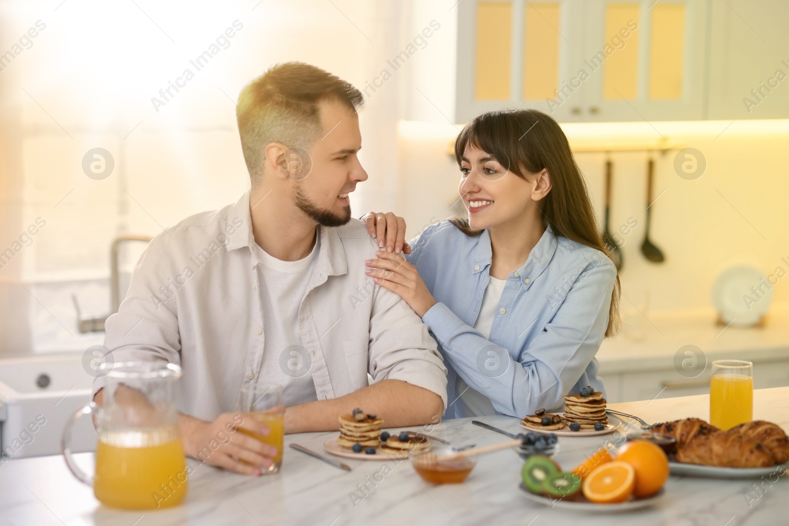 Image of Happy couple having breakfast in kitchen on sunny morning