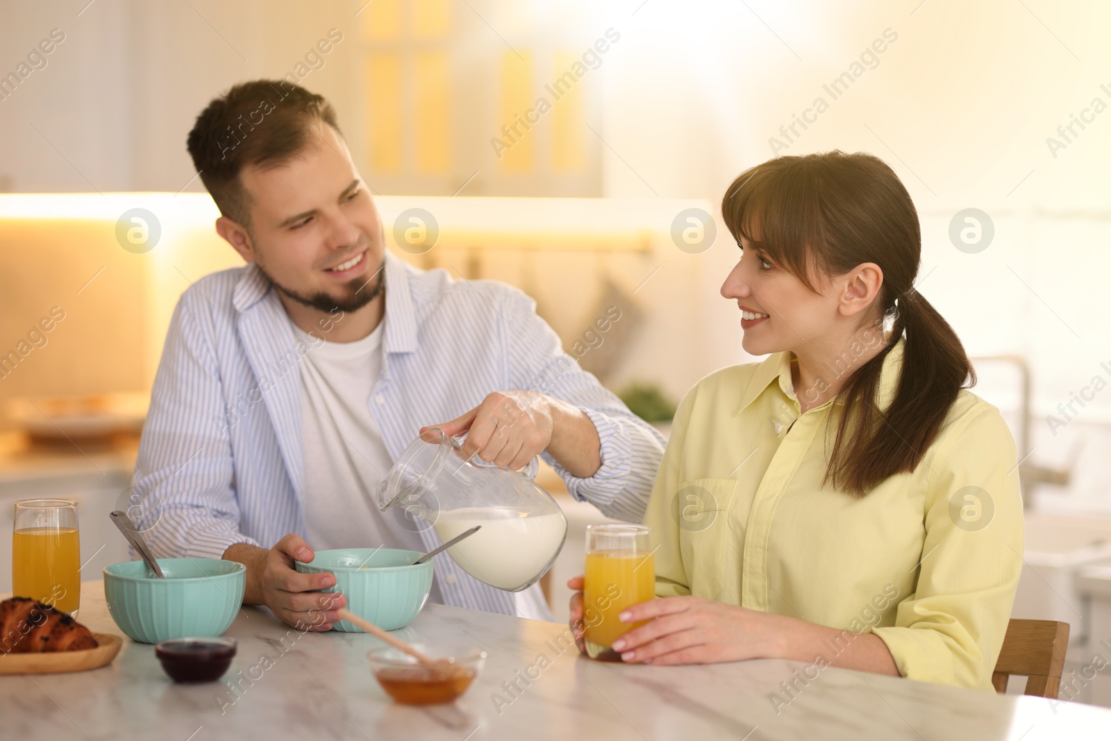 Image of Happy couple having breakfast in kitchen on sunny morning