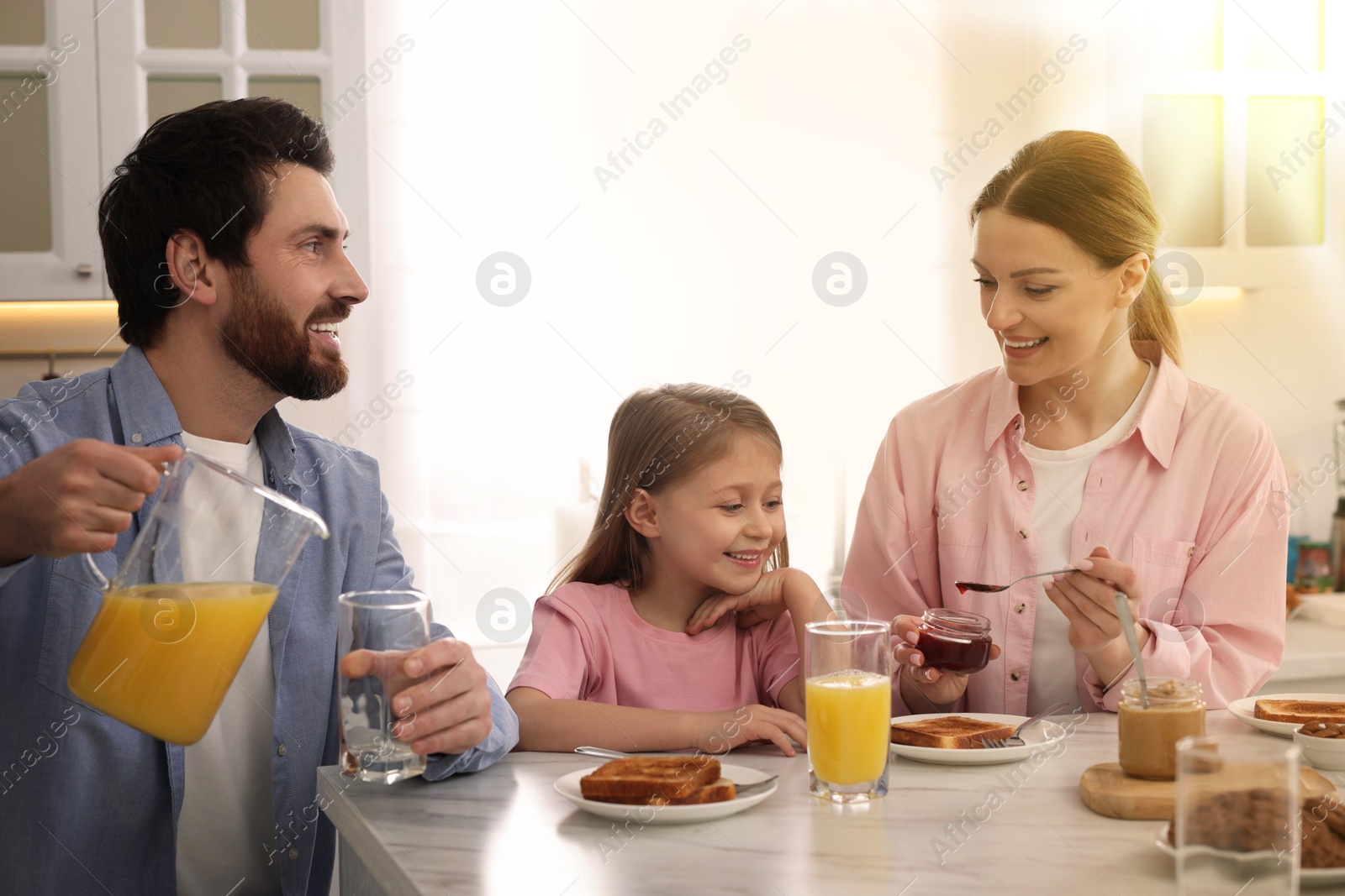 Image of Happy family having breakfast at table in kitchen on sunny morning