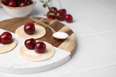 Photo of Process of making dumplings (varenyky) with cherries. Raw dough and ingredients on white table, closeup