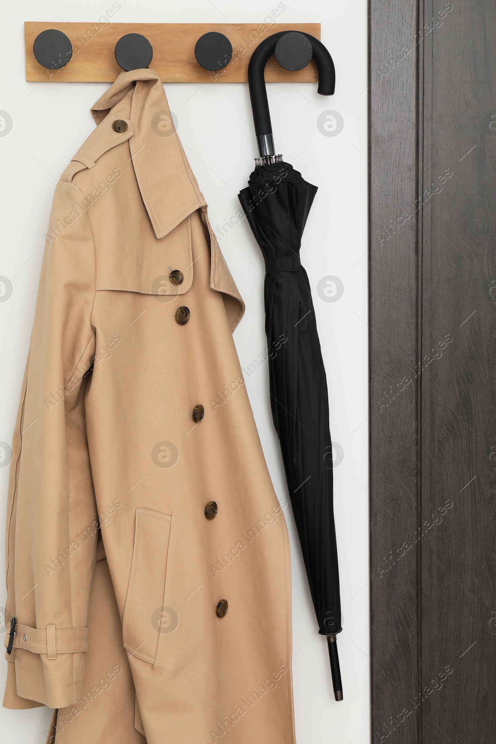 Photo of Black umbrella and coat on rack in hallway