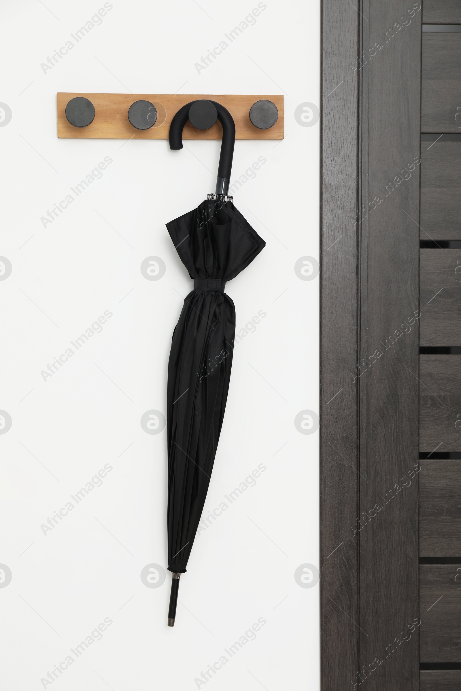 Photo of Black umbrella on coat rack in hallway