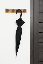 Black umbrella on coat rack in hallway