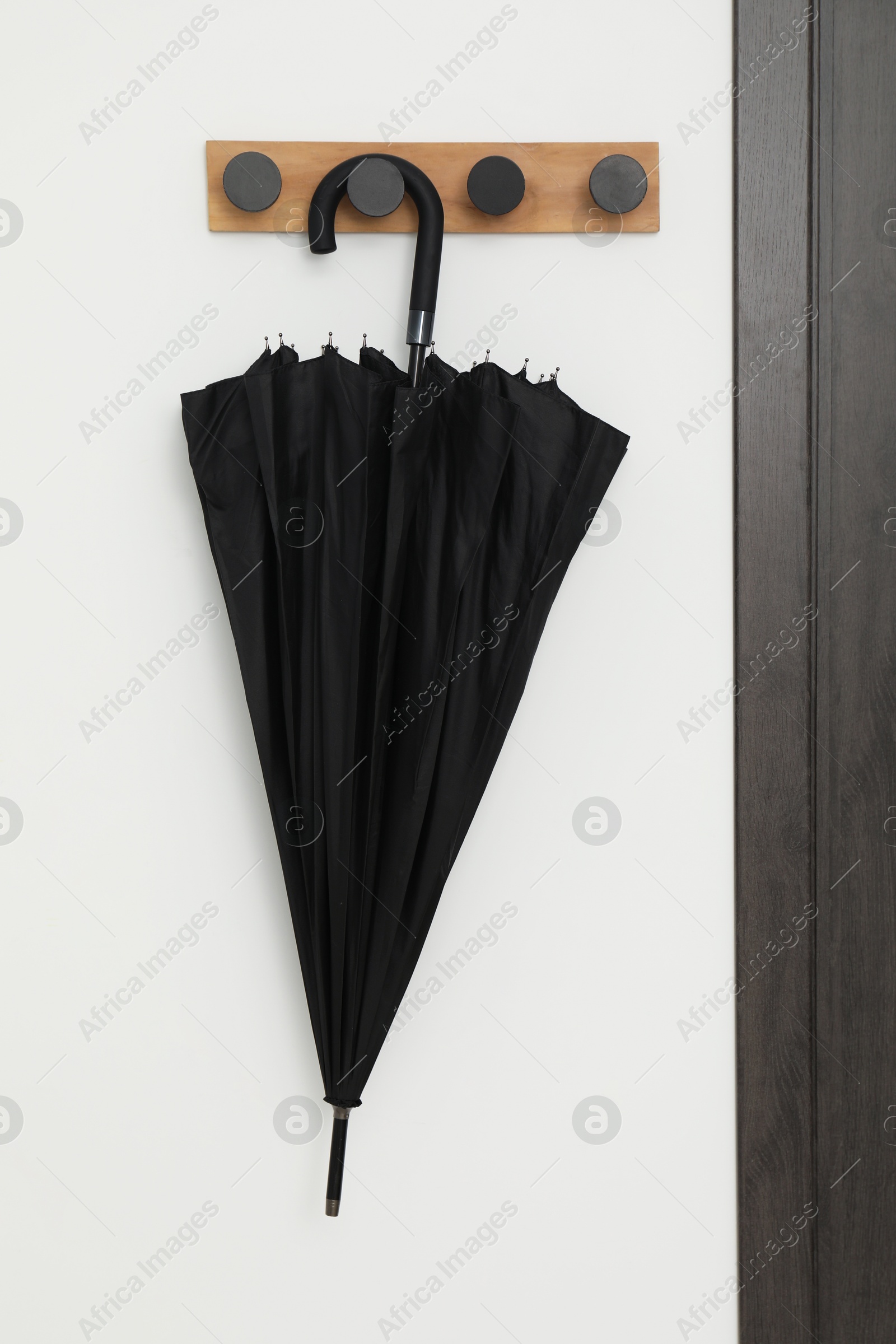 Photo of Black umbrella on coat rack in hallway