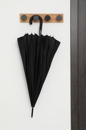 Black umbrella on coat rack in hallway