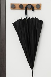 Black umbrella on coat rack in hallway