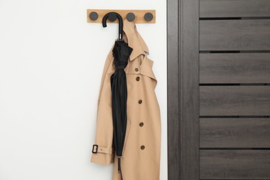 Black umbrella and coat on rack in hallway