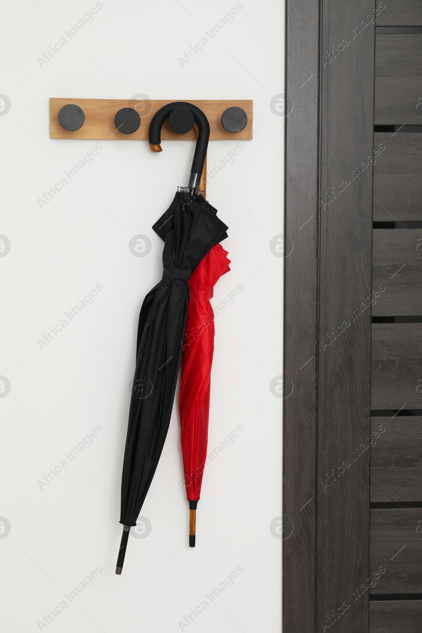 Photo of Black and red umbrellas on rack in hallway