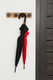 Black and red umbrellas on rack in hallway