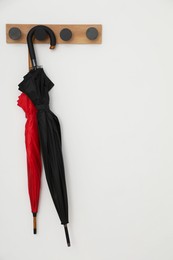 Photo of Black and red umbrellas on rack in hallway, space for text