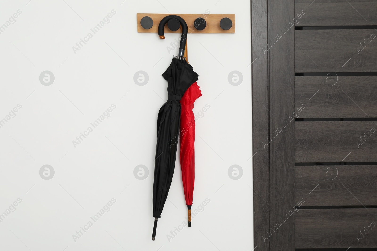 Photo of Black and red umbrellas on rack in hallway